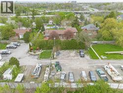 Expansive lot featuring a large gravel parking area, mature trees, and a green space -