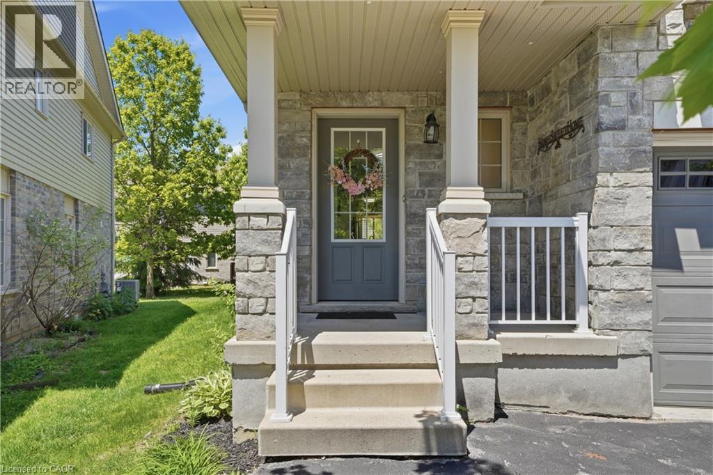 Stone veneer facade with a covered entry, featuring white support columns and railings - 7 Upper Mercer Street Unit# G30, Kitchener, ON - Outdoor With Facade