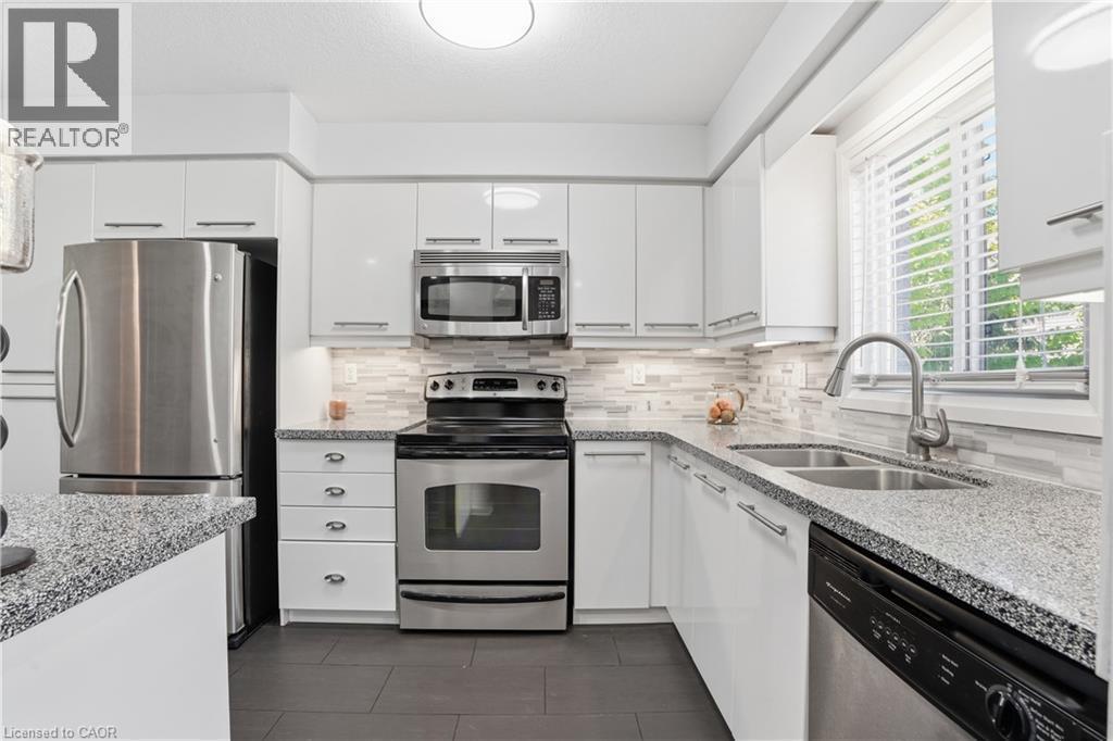 Modern kitchen featuring white cabinetry, stainless steel appliances, speckled countertops, and a subway tile backsplash - 7 Upper Mercer Street Unit# G30, Kitchener, ON - Indoor Photo Showing Kitchen With Stainless Steel Kitchen With Double Sink With Upgraded Kitchen