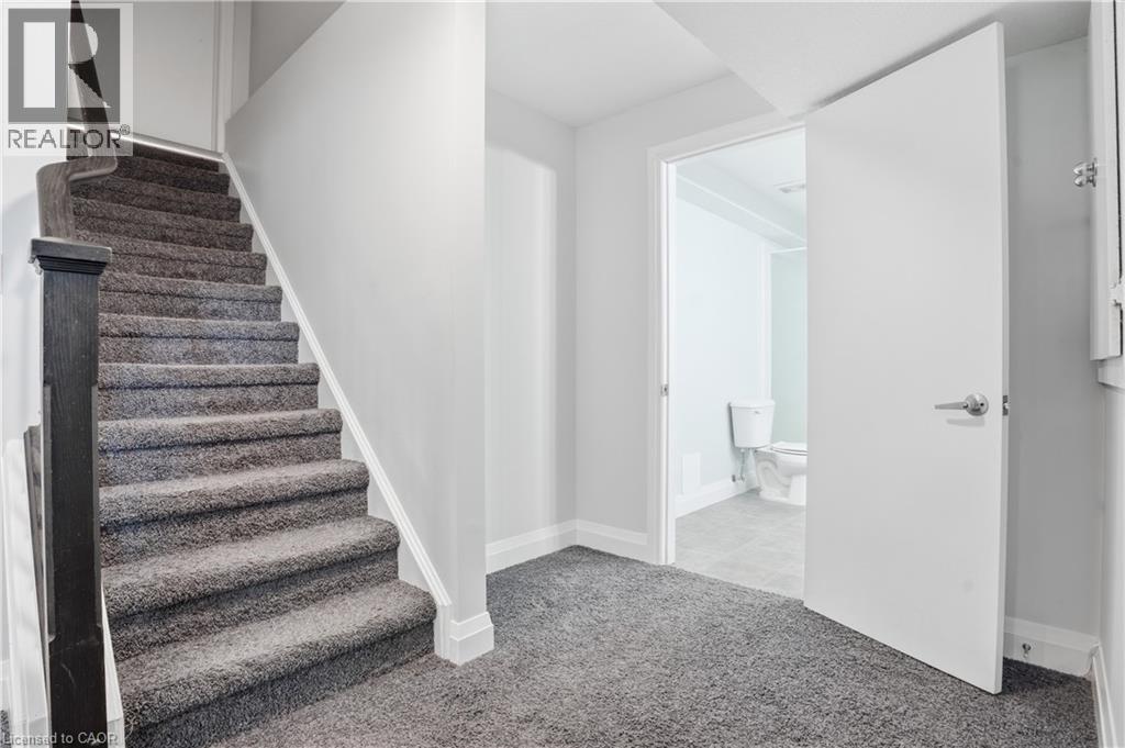 Plush gray carpeted staircase with dark wood newel post and handrail - 7 Upper Mercer Street Unit# G30, Kitchener, ON - Indoor Photo Showing Other Room