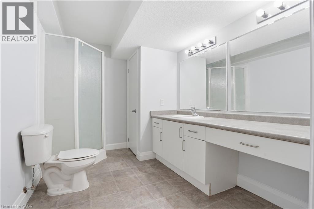 Bathroom featuring a white vanity with integrated sink, expansive countertop, and chrome fixtures - 7 Upper Mercer Street Unit# G30, Kitchener, ON - Indoor Photo Showing Bathroom