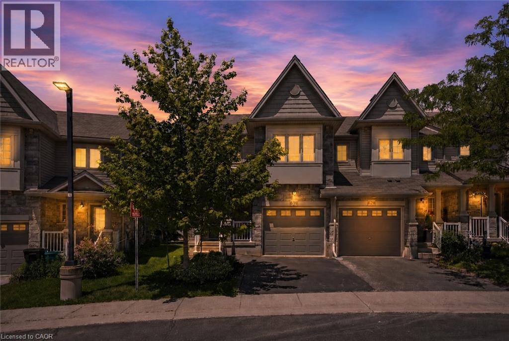 Townhome exterior featuring gabled roofs, stone and siding accents, attached garages, and a paved driveway - 7 Upper Mercer Street Unit# G30, Kitchener, ON - Outdoor With Facade