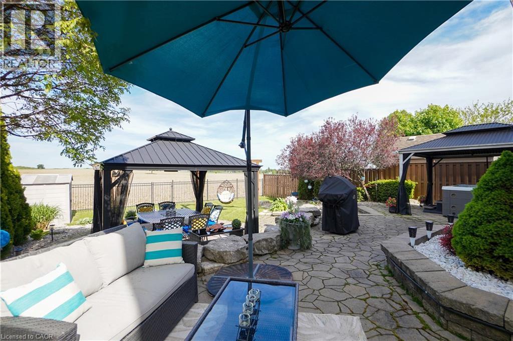 Expansive backyard featuring a natural stone patio, two permanent gazebos, mature plantings, and a privacy fence - 365 Poldon Drive, Norwich, ON