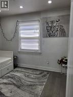 Room featuring dark wood-finish flooring, recessed ceiling lighting, and a window with horizontal blinds -