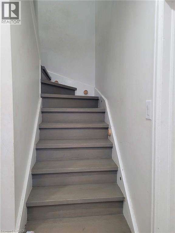 Staircase featuring wood-finish treads and risers, white painted stringers, and light gray wall paint - 153 Arnold Street, Kitchener, ON