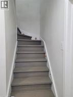 Staircase featuring wood-finish treads and risers, white painted stringers, and light gray wall paint -