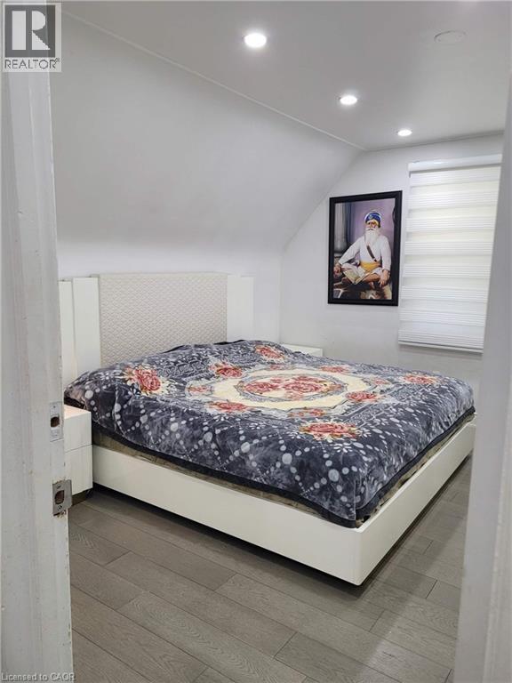 Bedroom featuring a sloped ceiling with recessed lighting, wood-finish flooring, and a window with horizontal blinds - 153 Arnold Street, Kitchener, ON