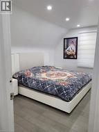 Bedroom featuring a sloped ceiling with recessed lighting, wood-finish flooring, and a window with horizontal blinds -