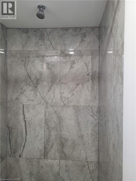 Shower enclosure featuring large format grey stone-look tile walls and a ceiling-mounted shower head - 153 Arnold Street, Kitchener, ON