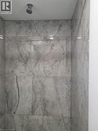 Shower enclosure featuring large format grey stone-look tile walls and a ceiling-mounted shower head -