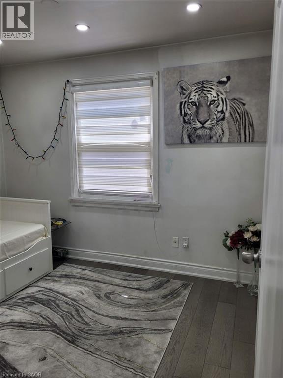 Room featuring dark wood-finish flooring, recessed ceiling lighting, and a window with horizontal blinds - 153 Arnold Street, Kitchener, ON