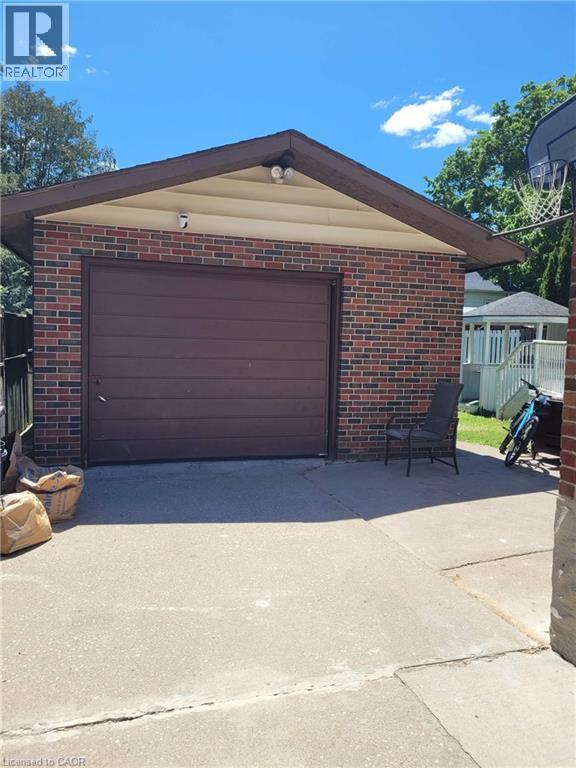 Detached brick garage with a pitched roof and a brown panel garage door - 153 Arnold Street, Kitchener, ON