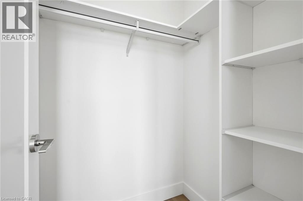 Walk-in closet featuring white built-in shelving, a hanging rod, and baseboard trim - 7 Mabelle Avenue Unit# Ph07, Toronto, ON