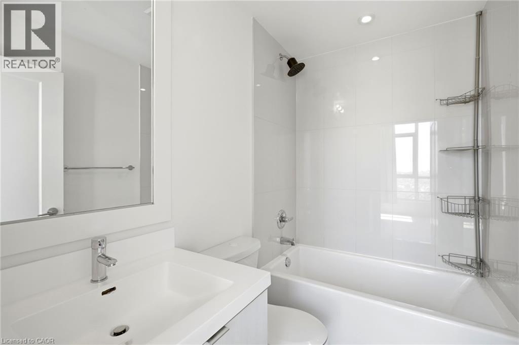 Contemporary bathroom featuring a white vanity with integrated sink, chrome faucet, a framed wall mirror, and a white bathtub with subway-tiled surround - 7 Mabelle Avenue Unit# Ph07, Toronto, ON