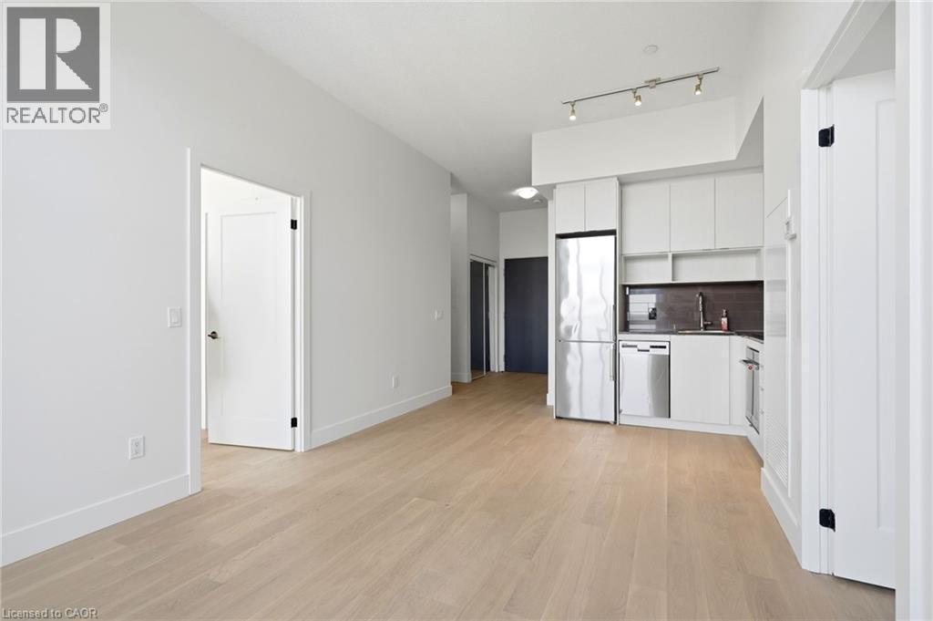 Open-concept living area featuring light wood-finish flooring, white walls, and a contemporary kitchen - 7 Mabelle Avenue Unit# Ph07, Toronto, ON