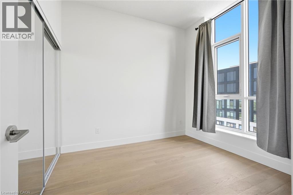 Bright interior featuring wood-finish flooring, white walls, and a large window with white framing - 7 Mabelle Avenue Unit# Ph07, Toronto, ON
