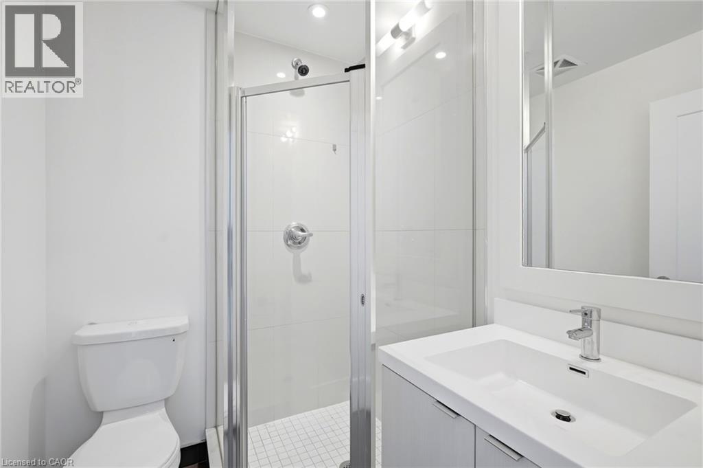 Bathroom featuring a white vanity with integrated sink, chrome faucet, wall-mounted mirror, and glass-enclosed shower with tile surround - 7 Mabelle Avenue Unit# Ph07, Toronto, ON