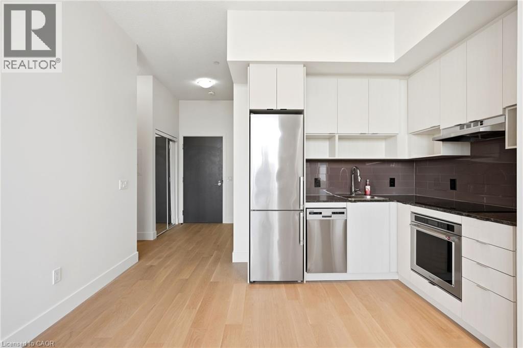 Modern kitchen featuring white cabinetry, stainless steel appliances, dark stone countertops, and a subway tile backsplash - 7 Mabelle Avenue Unit# Ph07, Toronto, ON