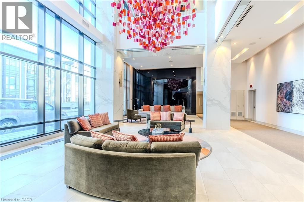 Lobby area featuring full-height window walls, a striking multi-colored chandelier, polished tile flooring, and integrated wall art - 7 Mabelle Avenue Unit# Ph07, Toronto, ON