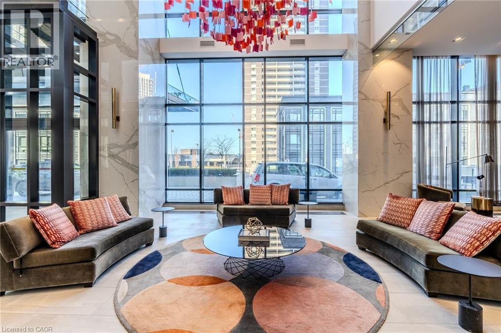 Grand lobby space featuring a striking red and orange geometric chandelier, floor-to-ceiling windows, and polished marble wall accents - 7 Mabelle Avenue Unit# Ph07, Toronto, ON
