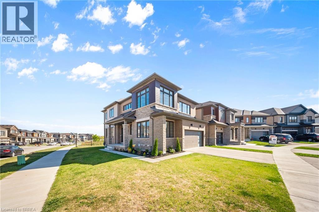 View of front of house featuring a residential view, concrete driveway, a front lawn, brick siding, and a garage - 1 Bee Crescent, Brantford, ON