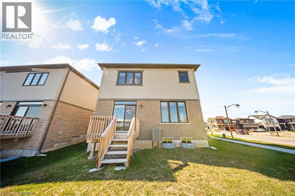 Back of house featuring a yard, brick siding, and a residential view - 1 Bee Crescent, Brantford, ON