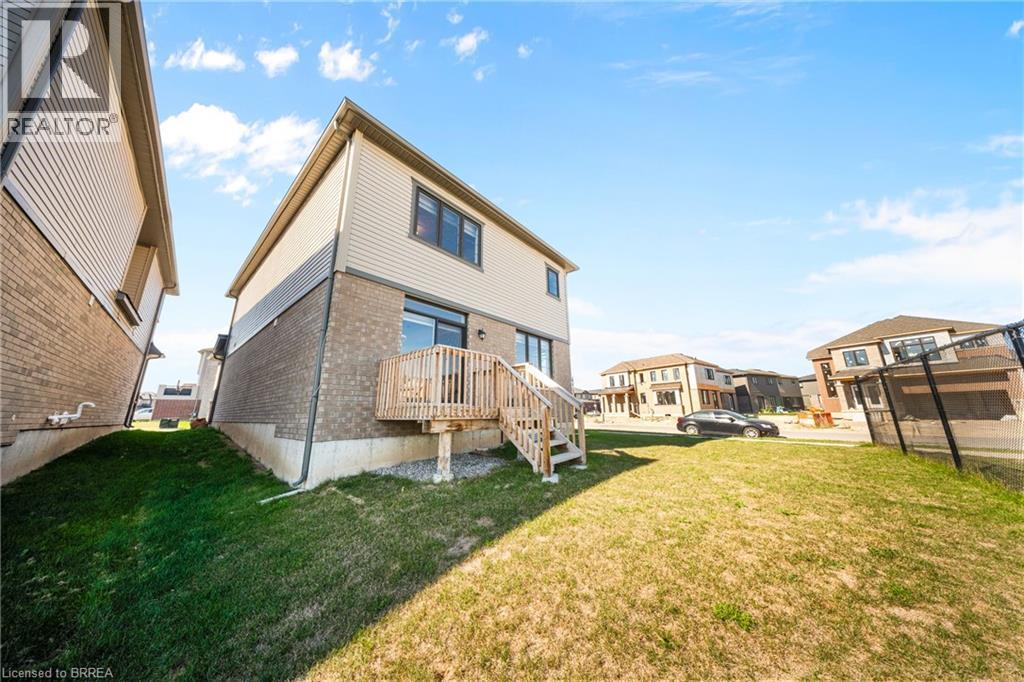 Rear view of property with brick siding, a lawn, and a residential view - 1 Bee Crescent, Brantford, ON