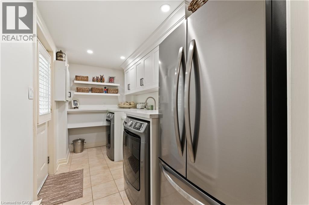 Frigidare fridge, washer, dryer. Gravelle white shaker cabinetry. Quartz countertop. Deep sink with Kohler handspray. Main floor. Side door. Adjoins mudroom. - 3040 First Street, Burlington, ON - Outdoor With In Ground Pool