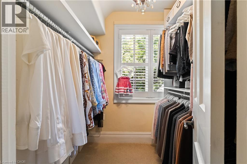 Primary bedroom closet. California shutters. Chandelier. Generous amount of shelving. - 3040 First Street, Burlington, ON - Indoor With Storage