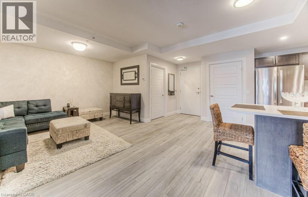 Open-concept living area featuring wood-finish flooring, recessed lighting, and a kitchen island with a light-toned countertop - 5 Wake Robin Drive Unit# 107, Kitchener, ON