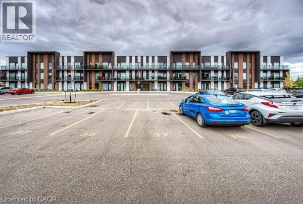 Contemporary apartment building featuring a multi-story facade with balconies, dark vertical accents, and light-colored siding - 5 Wake Robin Drive Unit# 107, Kitchener, ON