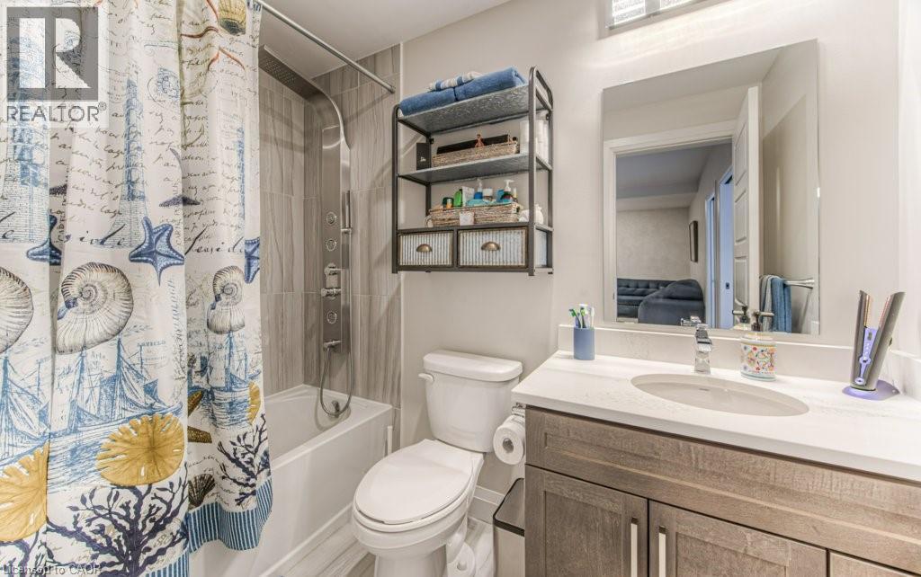 Bathroom featuring a white bathtub, a chrome multi-function shower panel, and light-toned tile surround - 5 Wake Robin Drive Unit# 107, Kitchener, ON