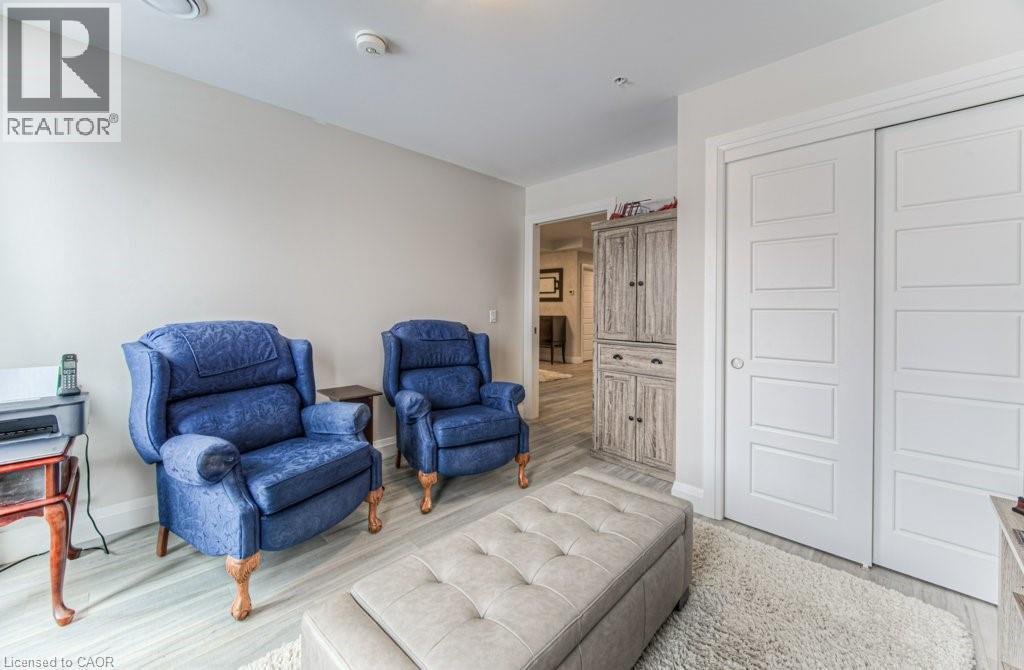 Light-toned wood-finish flooring extending into the hallway, complemented by a textured area rug - 5 Wake Robin Drive Unit# 107, Kitchener, ON