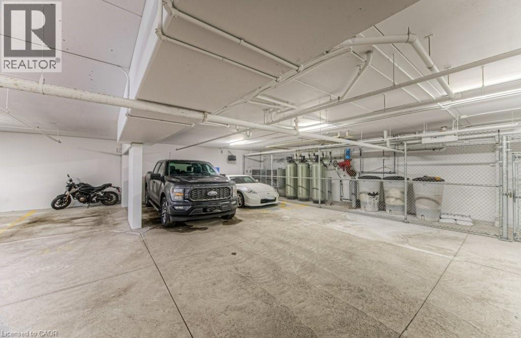 Spacious concrete parking garage with overhead piping and fluorescent lighting - 5 Wake Robin Drive Unit# 107, Kitchener, ON