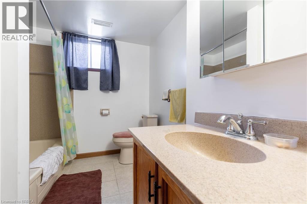 Bathroom featuring a vanity with a light-toned countertop and integrated sink, a chrome faucet, and a medicine cabinet with mirrored doors - 12 Spartan Drive, Brantford, ON - Indoor Photo Showing Bathroom