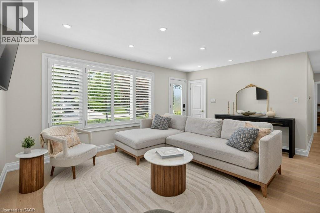 Bright living area featuring light wood-finish flooring, recessed lighting, and white plantation shutters - 603 Cornick Drive, Burlington, ON