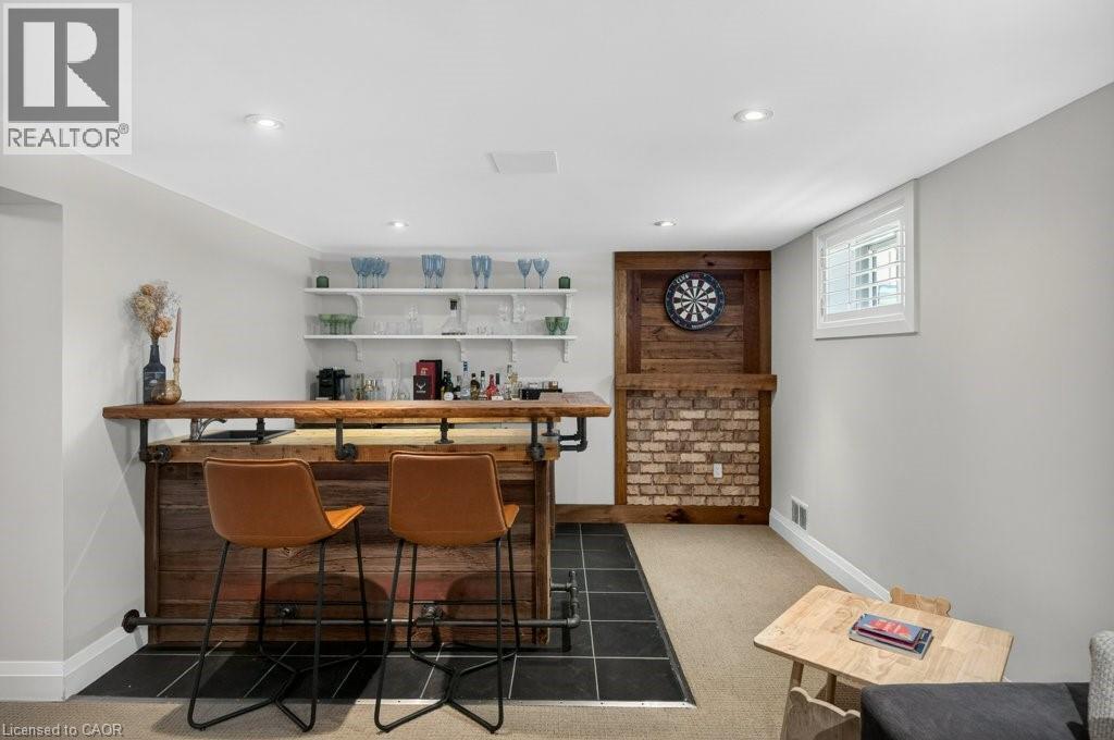 Custom-built wet bar featuring a wood-finish countertop, industrial-style pipe accents, and integrated shelving - 603 Cornick Drive, Burlington, ON