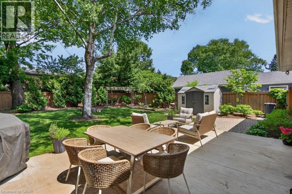 Expansive backyard featuring a large concrete patio, manicured lawn, and mature trees providing natural shade - 603 Cornick Drive, Burlington, ON