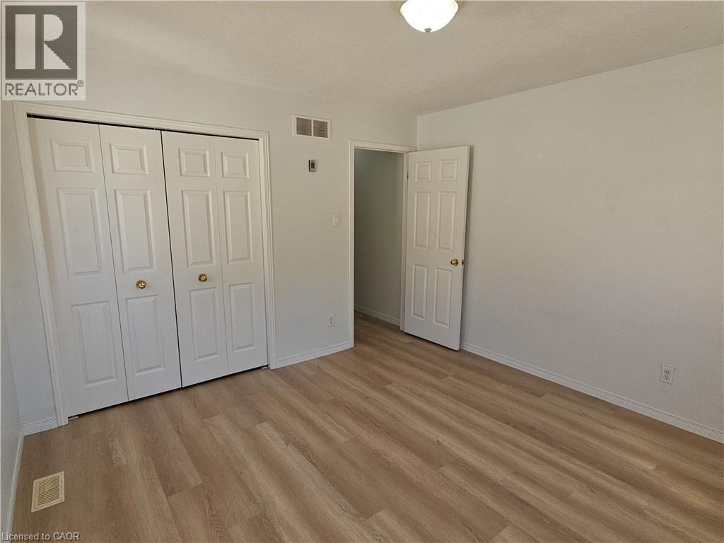 Room with wood-finish flooring, light-colored walls, and a ceiling-mounted light fixture - 390 Wake Robin Crescent, Kitchener, ON - Indoor Photo Showing Other Room