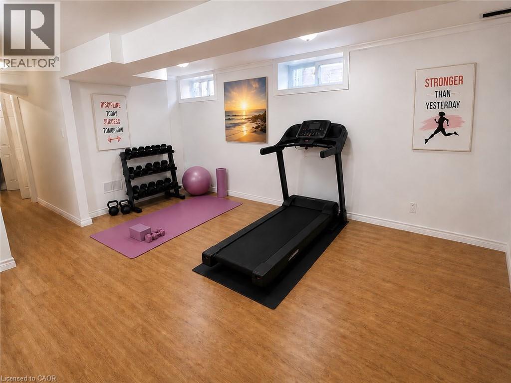Spacious lower-level room featuring wood-finish flooring, white walls, and recessed lighting - 390 Wake Robin Crescent, Kitchener, ON - Indoor