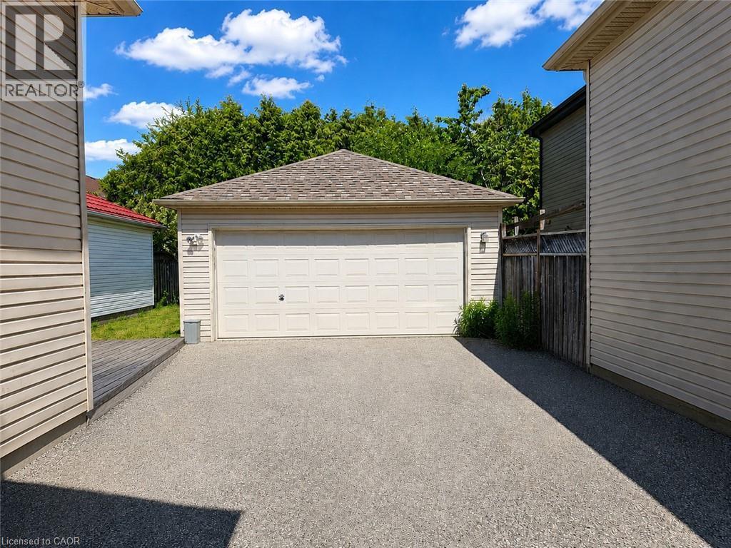 Detached garage with a paneled door, shingled roof, and exterior wall sconces - 390 Wake Robin Crescent, Kitchener, ON - Outdoor With Exterior