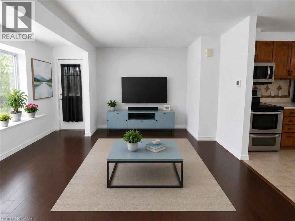 Bright living area featuring dark wood-finish flooring, white baseboards, and a large window with a deep sill - 390 Wake Robin Crescent, Kitchener, ON - Indoor Photo Showing Living Room