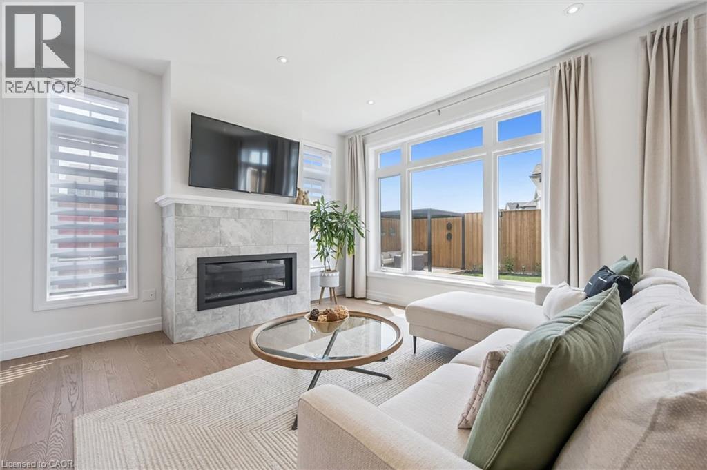 Living area featuring a tiled fireplace with an insert, a large picture window, recessed lighting, and wood-finish flooring - 30 Waterbow Trail, Kitchener, ON - Indoor Photo Showing Living Room With Fireplace