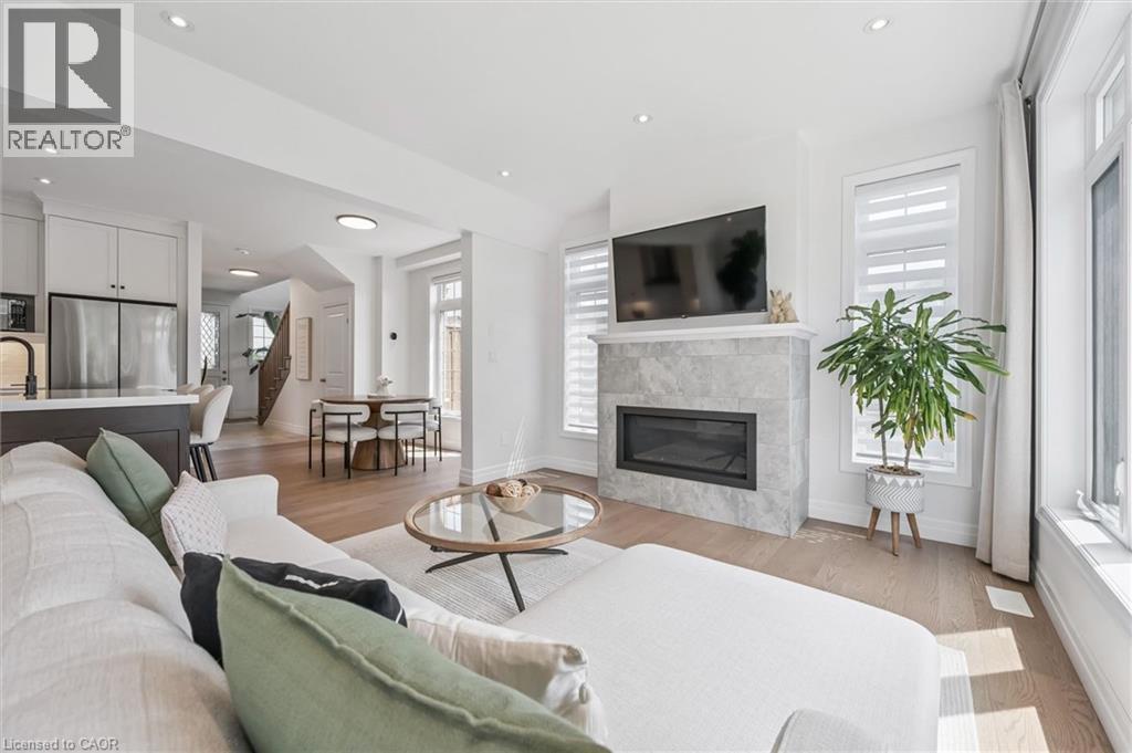Light wood-finish flooring complements white walls throughout this open-concept living area - 30 Waterbow Trail, Kitchener, ON - Indoor Photo Showing Living Room With Fireplace