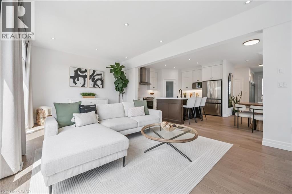 Open-concept living space featuring wood-finish flooring, recessed lighting, and large windows with full-height drapes - 30 Waterbow Trail, Kitchener, ON - Indoor Photo Showing Living Room