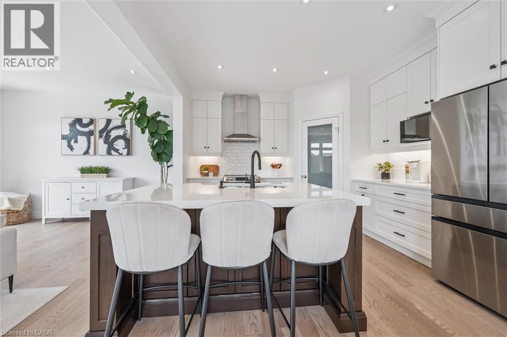 Spacious kitchen featuring a large central island with seating, white shaker cabinetry, stainless steel appliances, and light wood-finish flooring - 30 Waterbow Trail, Kitchener, ON - Indoor Photo Showing Kitchen With Stainless Steel Kitchen With Upgraded Kitchen