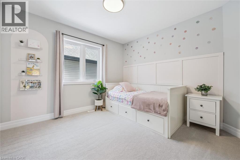 Light-filled room featuring a double window with blinds, soft gray carpeting, and a built-in wall paneling detail - 30 Waterbow Trail, Kitchener, ON - Indoor Photo Showing Bedroom