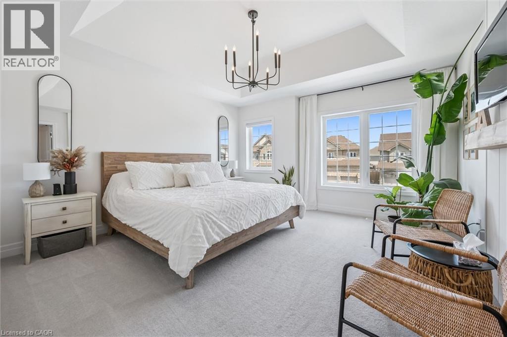 Bright bedroom featuring a tray ceiling, recessed lighting, and a modern chandelier - 30 Waterbow Trail, Kitchener, ON - Indoor Photo Showing Bedroom