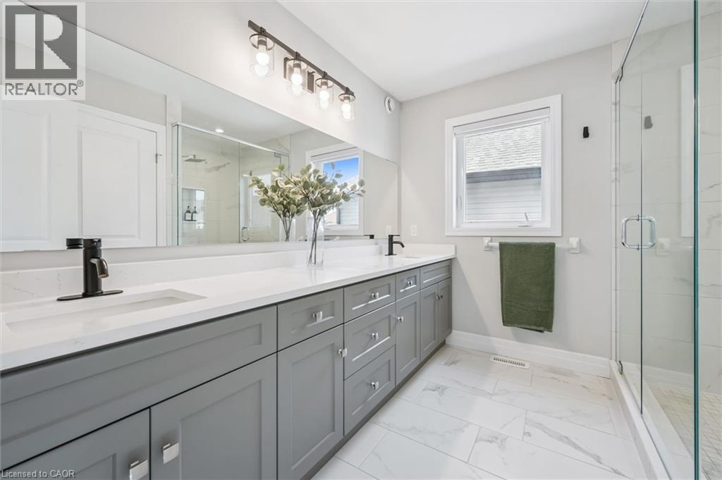 Contemporary bathroom featuring a dual vanity with light gray cabinetry, white countertops, and matte black fixtures - 30 Waterbow Trail, Kitchener, ON - Indoor Photo Showing Bathroom