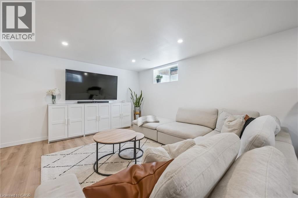 Spacious room featuring light-toned wood-finish flooring, recessed lighting, and a window - 30 Waterbow Trail, Kitchener, ON - Indoor Photo Showing Living Room